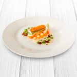 Foto receta de porcion de merluza con zanahoria sobre una cama de verduras y salsa blanca